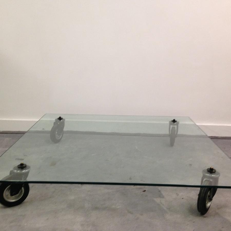 Low glass coffee table on industrial wheels