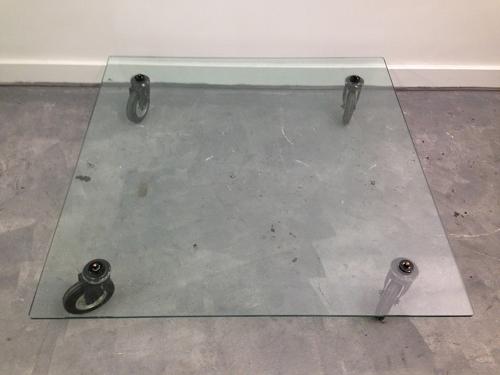 Low glass coffee table on industrial wheels