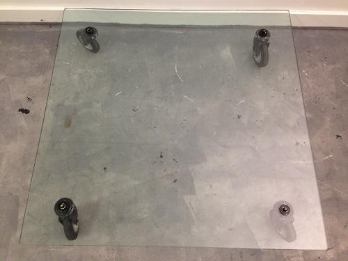 Low glass coffee table on industrial wheels