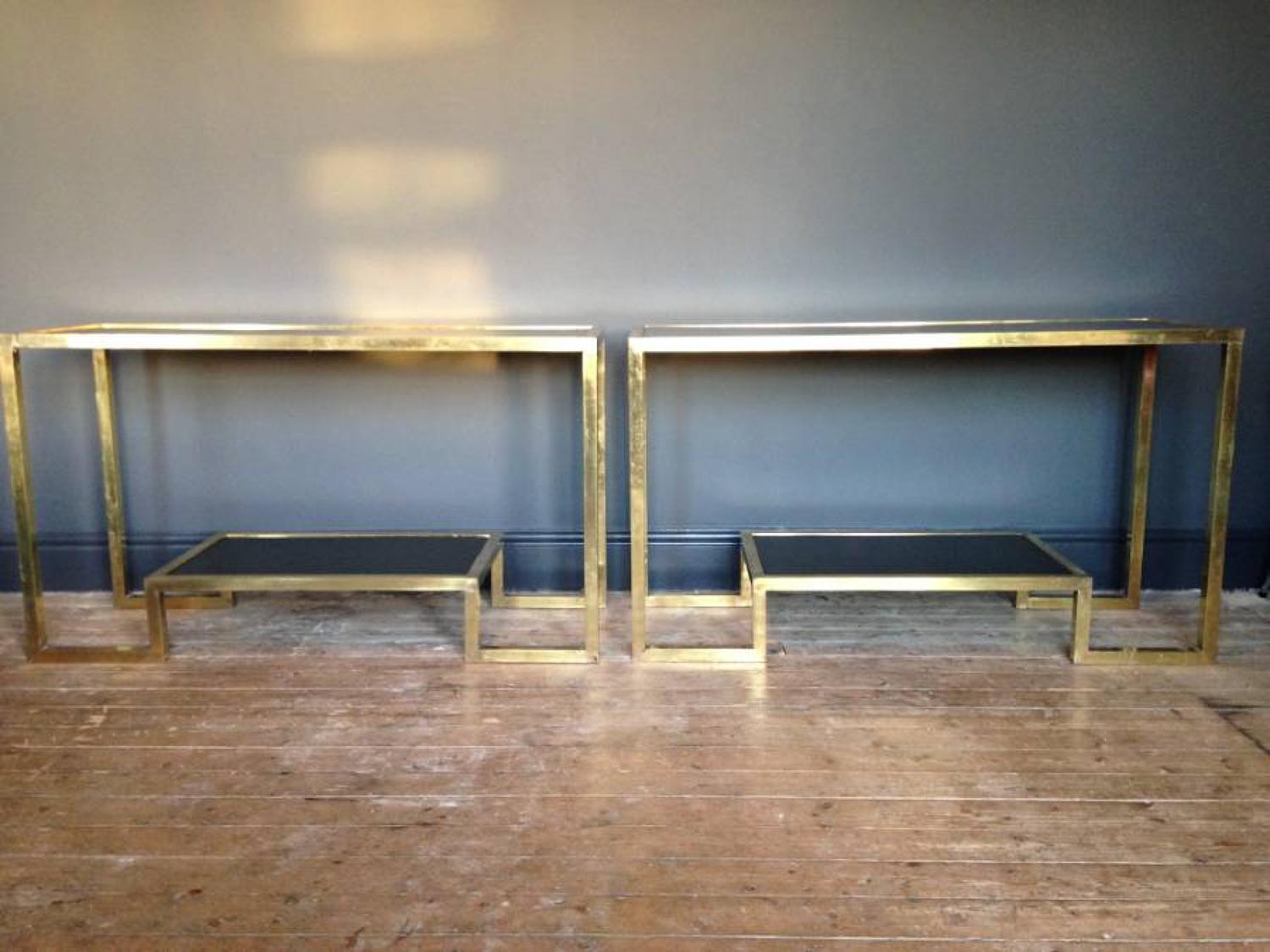 A pair of brass and glass console tables