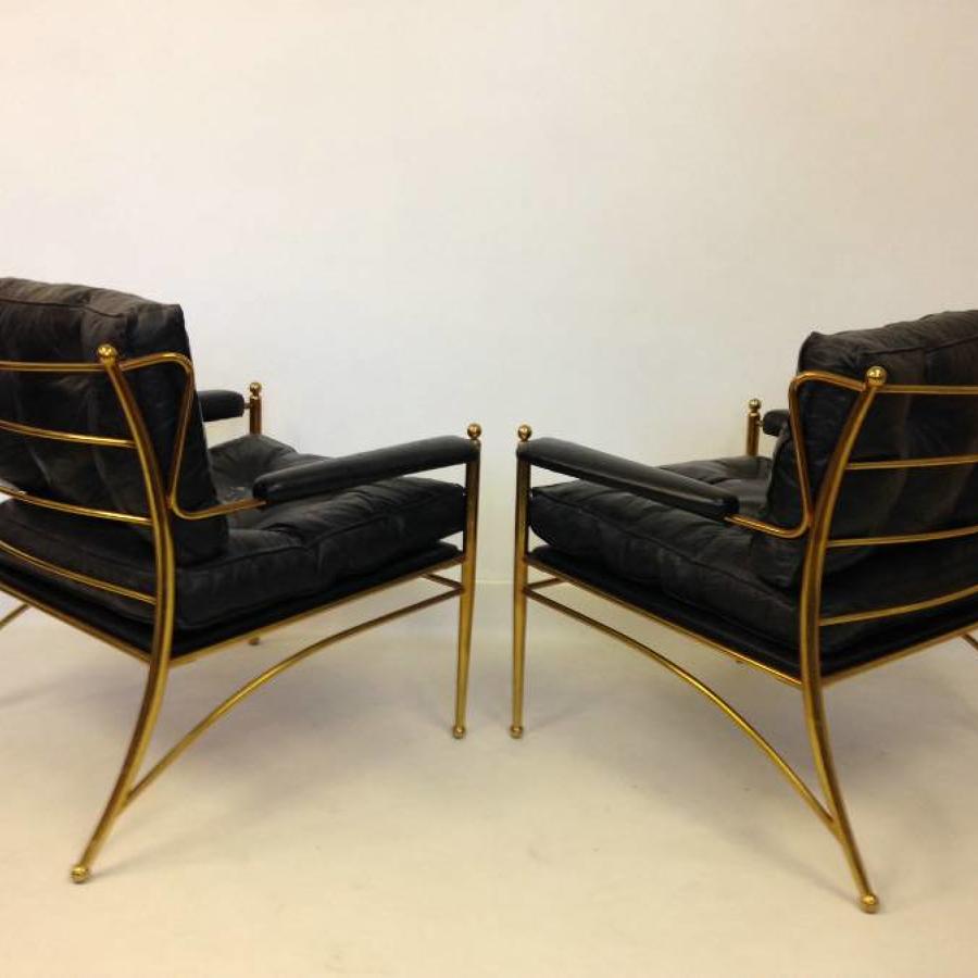 A pair of brass framed and leather armchairs
