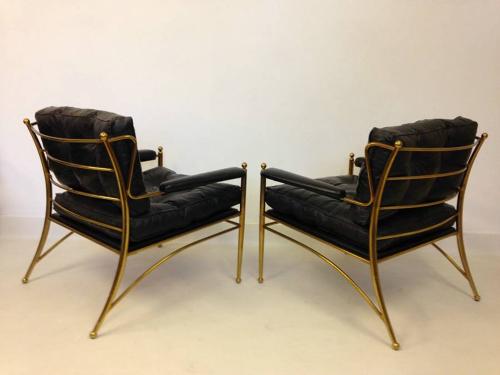 A pair of brass framed and leather armchairs