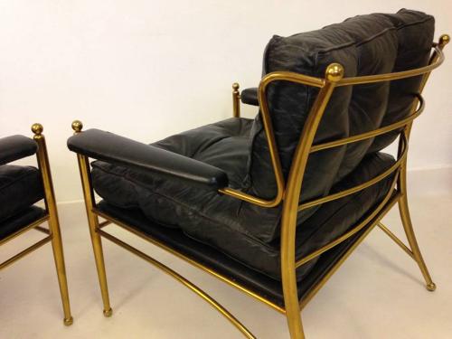 A pair of brass framed and leather armchairs