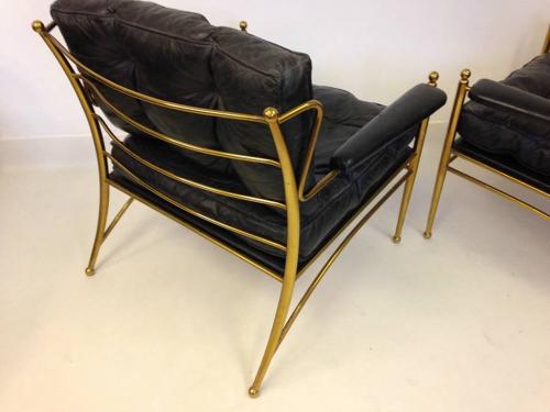 A pair of brass framed and leather armchairs